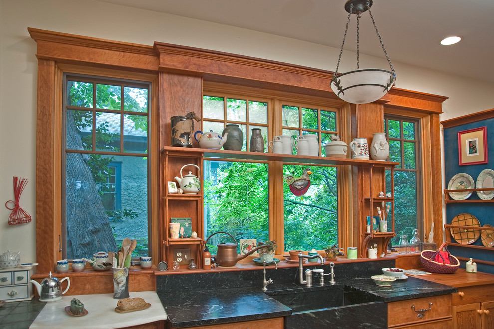 На фото: кухня у окна, среднего размера в стиле кантри с монолитной мойкой, открытыми фасадами, столешницей из талькохлорита и коричневым фартуком с