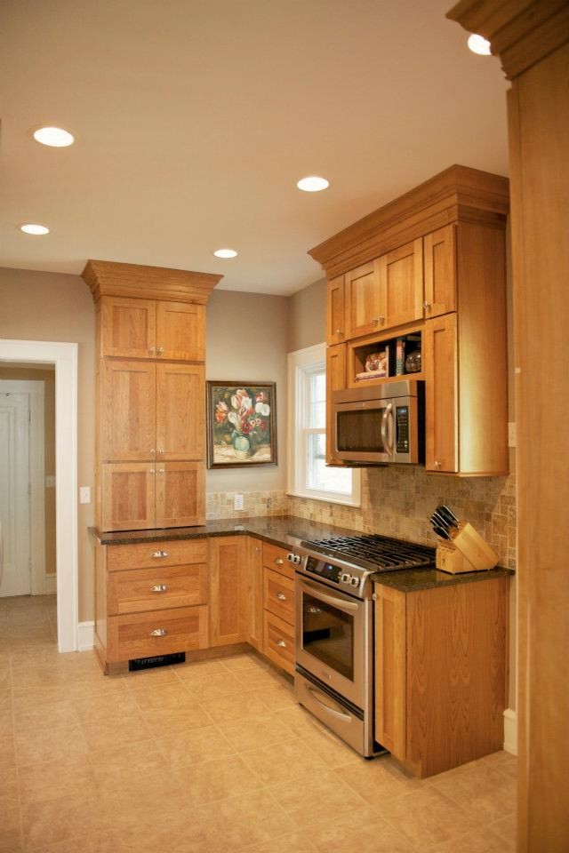 Amerikansk inredning av ett litet kök, med en undermonterad diskho, skåp i shakerstil, skåp i ljust trä, granitbänkskiva, beige stänkskydd, stänkskydd i stenkakel, rostfria vitvaror och travertin golv