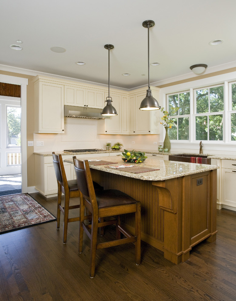 Eat-in kitchen - craftsman u-shaped medium tone wood floor and brown floor eat-in kitchen idea in Chicago with a farmhouse sink, recessed-panel cabinets, beige cabinets, granite countertops, beige backsplash, subway tile backsplash, paneled appliances, an island and beige countertops