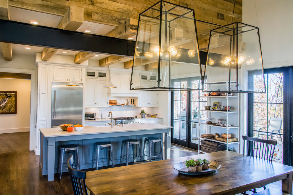 Example of a country galley dark wood floor and brown floor eat-in kitchen design in Other with a farmhouse sink, shaker cabinets, gray cabinets, white backsplash, stainless steel appliances and an island