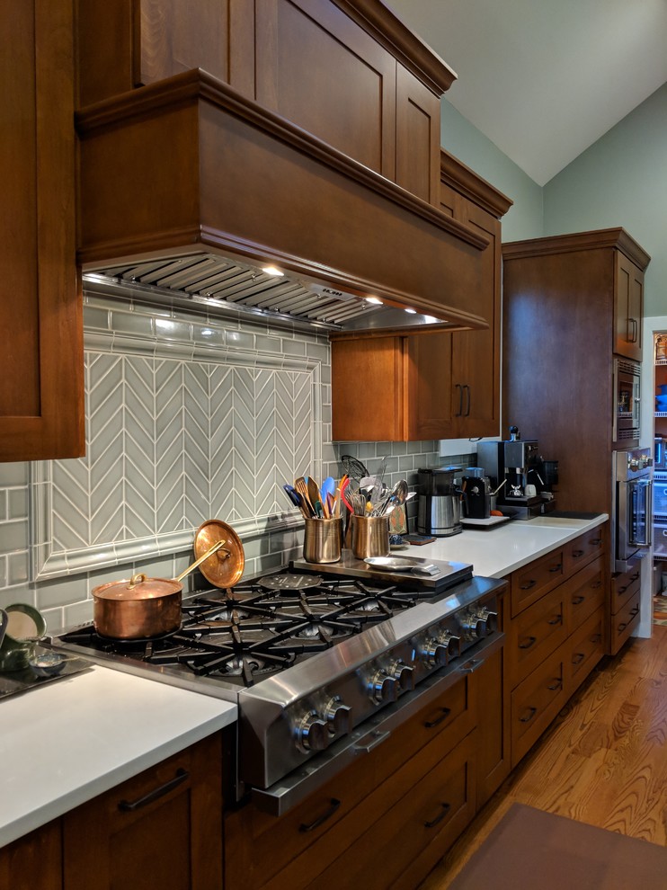 Foto på ett stort amerikanskt vit kök, med en köksö, skåp i shakerstil, skåp i mellenmörkt trä, granitbänkskiva, grönt stänkskydd, stänkskydd i porslinskakel, rostfria vitvaror, mellanmörkt trägolv, brunt golv och en rustik diskho