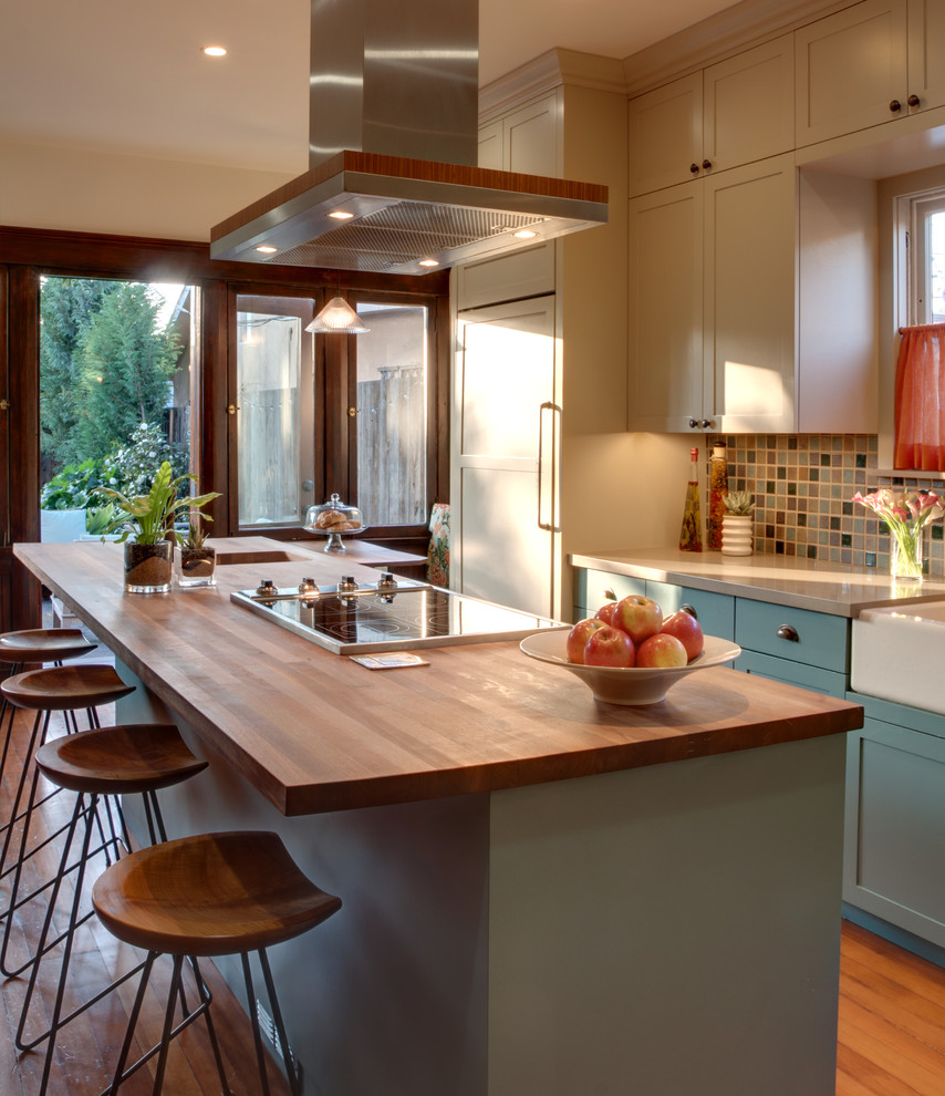 Example of a mid-sized classic galley medium tone wood floor eat-in kitchen design in Los Angeles with a farmhouse sink, quartz countertops, multicolored backsplash, beige cabinets, shaker cabinets, ceramic backsplash, an island and paneled appliances