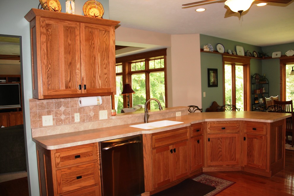 Amerikansk inredning av ett kök, med en nedsänkt diskho, laminatbänkskiva, stänkskydd i keramik, rostfria vitvaror och mellanmörkt trägolv