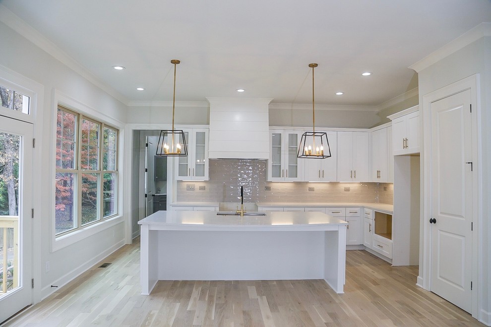 Inspiration for a medium sized traditional l-shaped open plan kitchen in Atlanta with a submerged sink, shaker cabinets, white cabinets, engineered stone countertops, grey splashback, ceramic splashback, stainless steel appliances, light hardwood flooring, an island, beige floors and grey worktops.