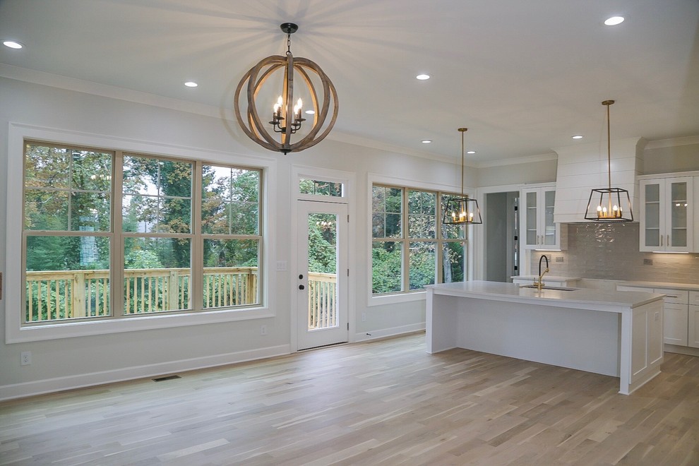 Inspiration for a mid-sized craftsman l-shaped light wood floor and beige floor open concept kitchen remodel in Atlanta with an undermount sink, shaker cabinets, white cabinets, quartz countertops, gray backsplash, ceramic backsplash, stainless steel appliances, an island and gray countertops
