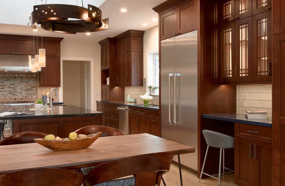 Immagine di una cucina american style con ante con riquadro incassato, ante in legno bruno, elettrodomestici in acciaio inossidabile, parquet chiaro e pavimento beige