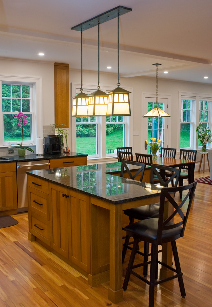 Foto på ett mellanstort amerikanskt flerfärgad kök och matrum, med en undermonterad diskho, skåp i mellenmörkt trä, granitbänkskiva, grönt stänkskydd, stänkskydd i tunnelbanekakel, rostfria vitvaror, mellanmörkt trägolv, en köksö och luckor med infälld panel