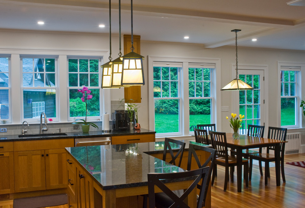 Amerikansk inredning av ett mellanstort flerfärgad flerfärgat kök och matrum, med en undermonterad diskho, skåp i mellenmörkt trä, granitbänkskiva, grönt stänkskydd, stänkskydd i tunnelbanekakel, rostfria vitvaror, mellanmörkt trägolv, en köksö och luckor med infälld panel