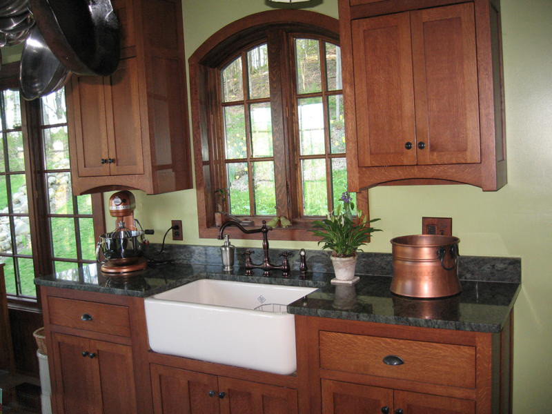 Inspiration for a mid-sized craftsman u-shaped porcelain tile eat-in kitchen remodel in New York with a farmhouse sink, flat-panel cabinets, medium tone wood cabinets, granite countertops, brown backsplash, stone slab backsplash, white appliances and a peninsula