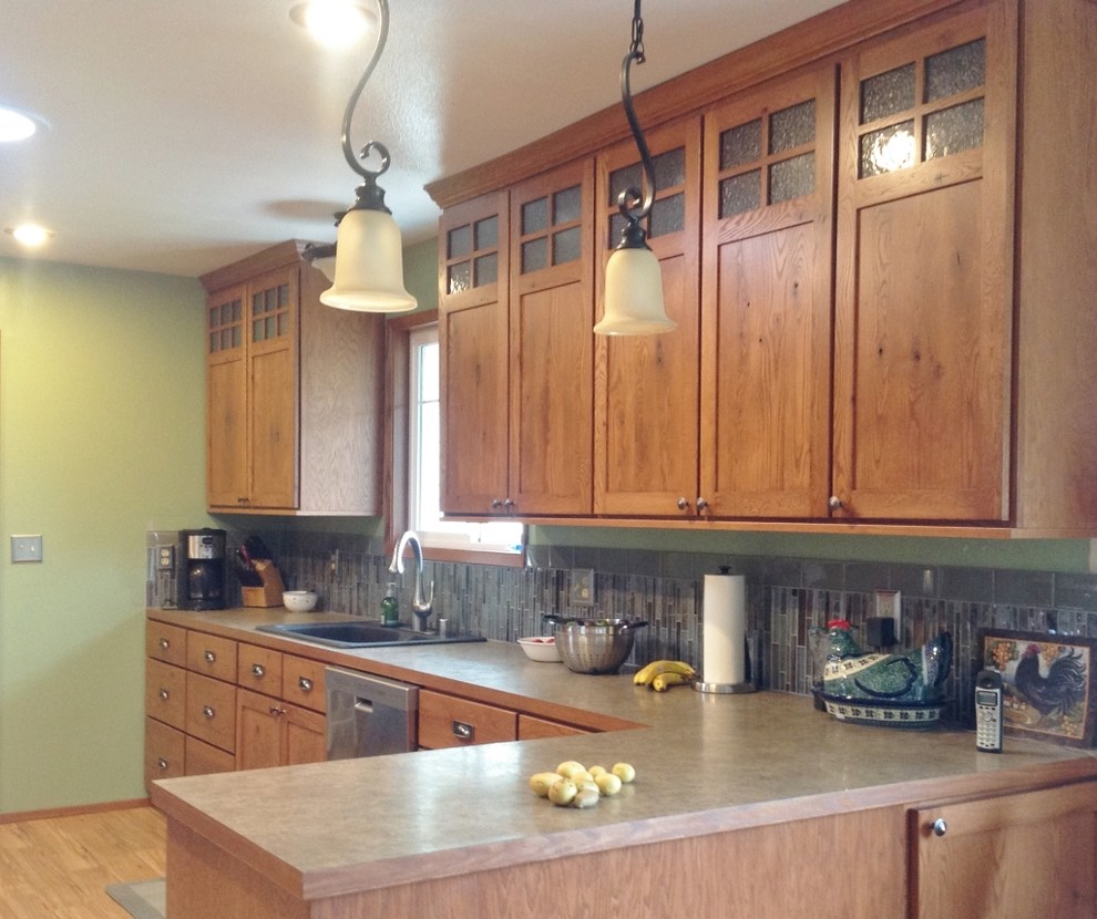 Bild på ett mellanstort amerikanskt kök och matrum, med skåp i shakerstil, skåp i mellenmörkt trä, laminatbänkskiva, flerfärgad stänkskydd, stänkskydd i glaskakel, rostfria vitvaror, mellanmörkt trägolv och en halv köksö
