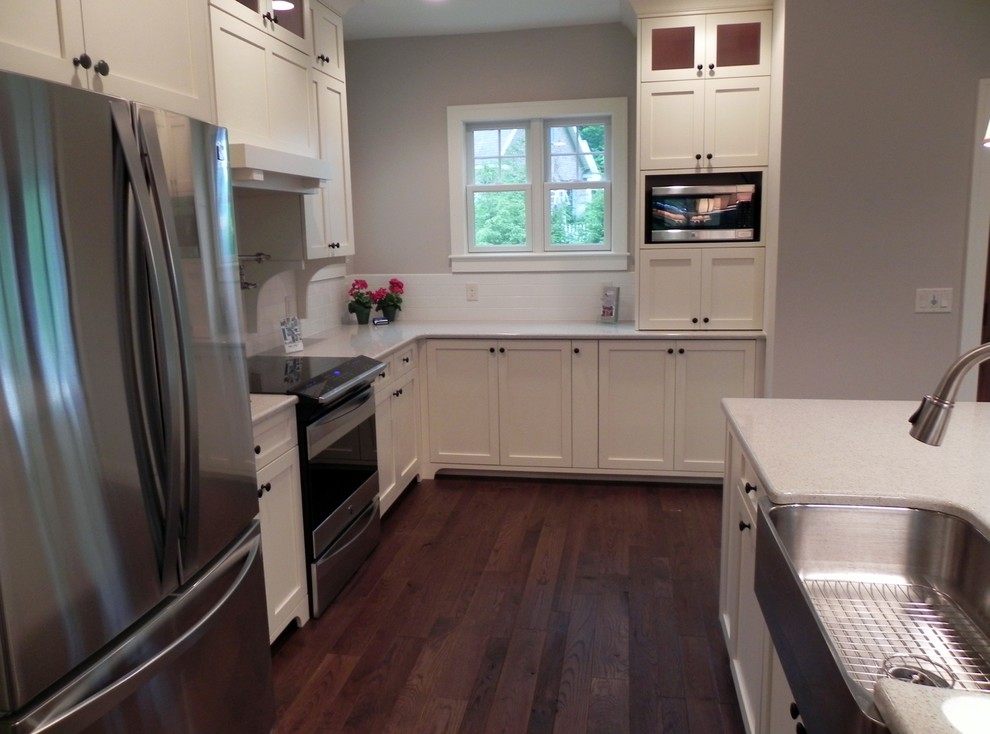 Example of a mid-sized arts and crafts galley dark wood floor kitchen design in Grand Rapids with a farmhouse sink, recessed-panel cabinets, white cabinets and stainless steel appliances