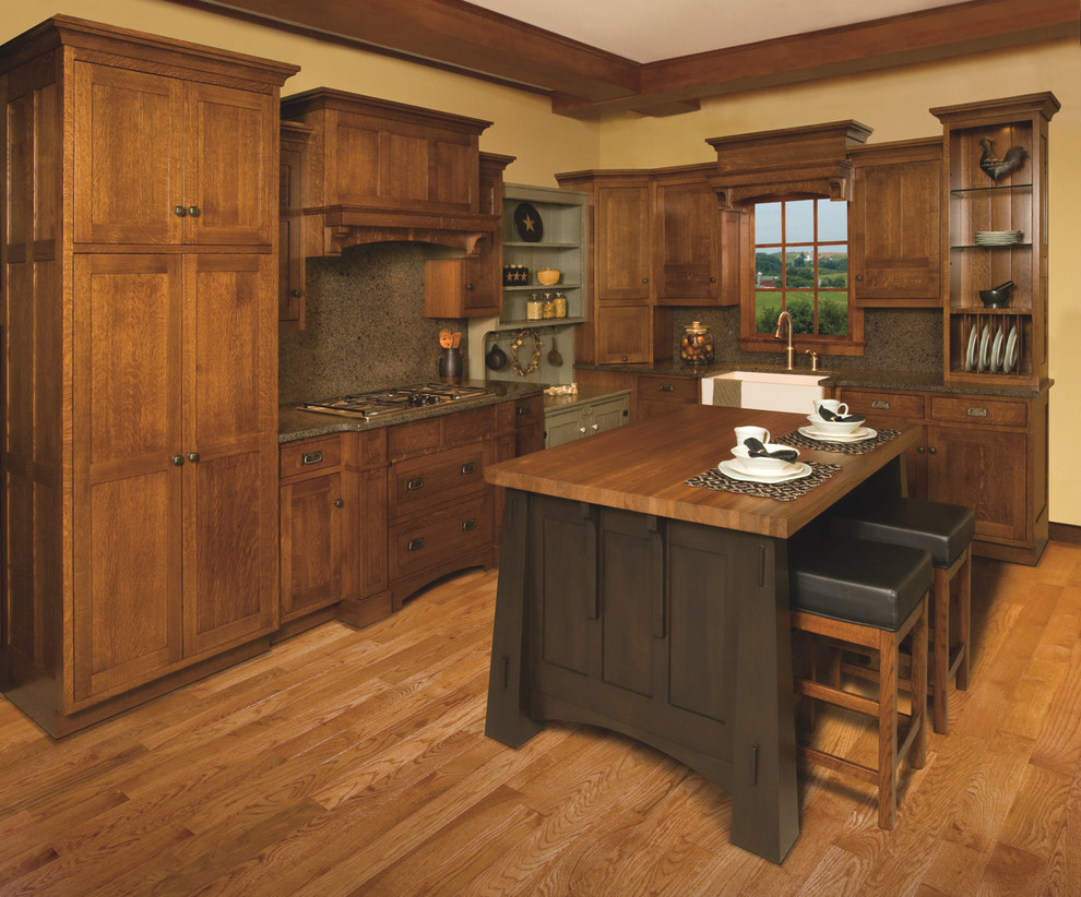 Cette photo montre une cuisine craftsman en L et bois foncé avec un placard à porte plane, un plan de travail en quartz modifié, un électroménager en acier inoxydable et un évier de ferme.