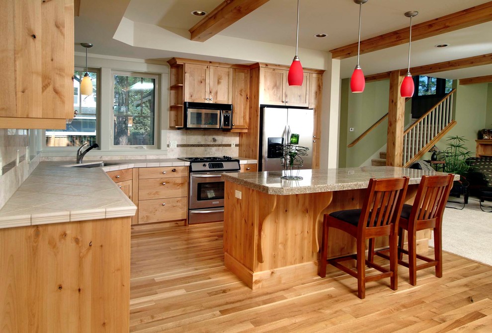 Exemple d'une cuisine craftsman en bois brun avec un évier 2 bacs, un placard avec porte à panneau surélevé, un plan de travail en granite, un électroménager en acier inoxydable, un sol en bois brun et îlot.