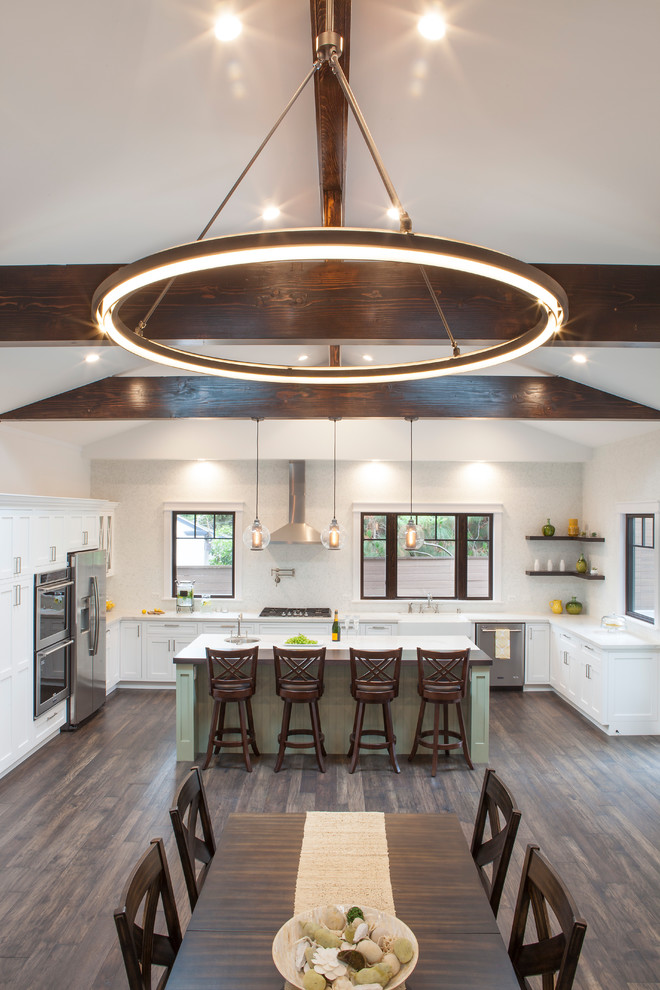 Inspiration for a large craftsman l-shaped medium tone wood floor and brown floor eat-in kitchen remodel in Los Angeles with a farmhouse sink, shaker cabinets, green cabinets, quartz countertops, white backsplash, glass sheet backsplash, stainless steel appliances and an island