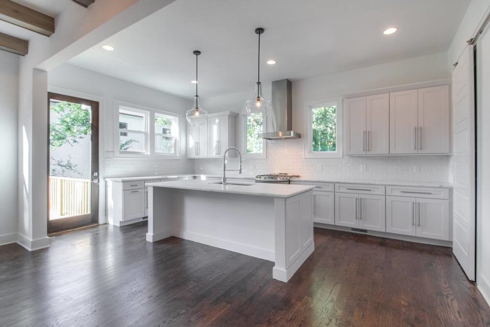 Open concept kitchen - large transitional l-shaped dark wood floor open concept kitchen idea in Nashville with a single-bowl sink, shaker cabinets, white cabinets, quartzite countertops, white backsplash, subway tile backsplash, stainless steel appliances and an island