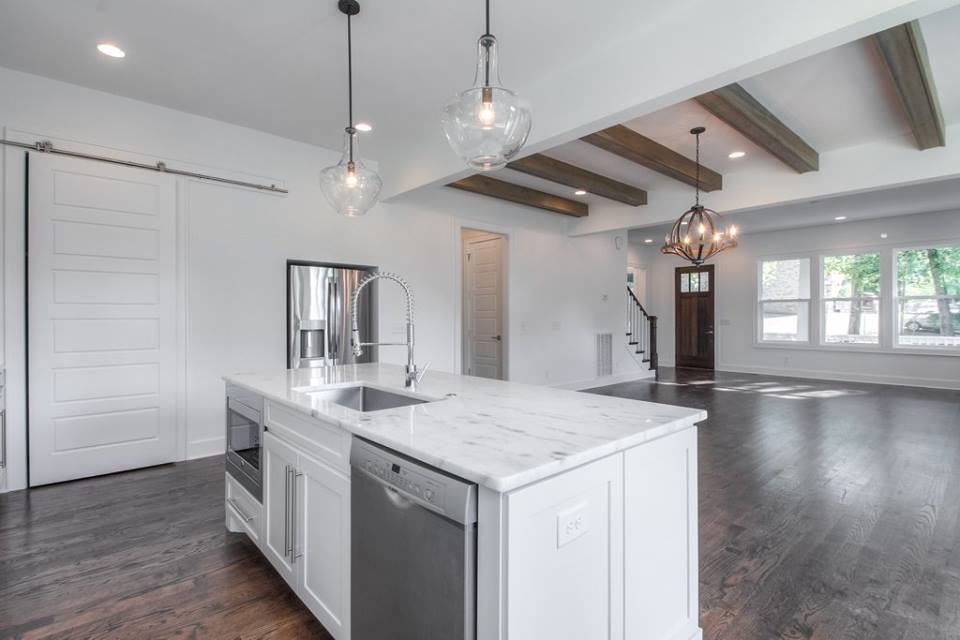 Photo of a large traditional l-shaped open plan kitchen in Nashville with a single-bowl sink, shaker cabinets, white cabinets, quartz worktops, white splashback, metro tiled splashback, stainless steel appliances, dark hardwood flooring and an island.