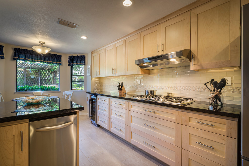 Eat-in kitchen - mid-sized contemporary l-shaped porcelain tile eat-in kitchen idea in Sacramento with a farmhouse sink, recessed-panel cabinets, light wood cabinets, granite countertops, beige backsplash, glass tile backsplash, stainless steel appliances and an island