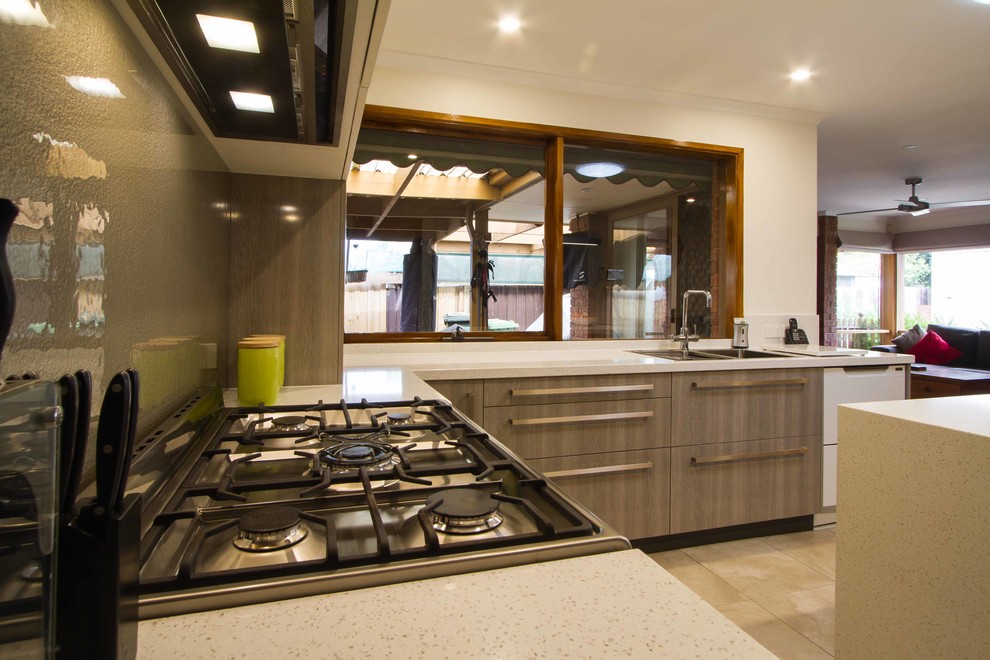 Esempio di una cucina minimal di medie dimensioni con ante lisce, top in quarzo composito, paraspruzzi a effetto metallico e paraspruzzi con lastra di vetro