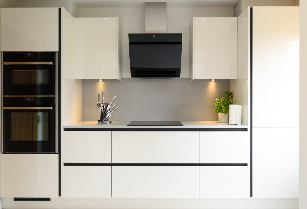 Idéer för ett mellanstort modernt grå kök, med en undermonterad diskho, släta luckor, bänkskiva i kvarts, grått stänkskydd, stänkskydd i sten, svarta vitvaror, klinkergolv i keramik och vitt golv