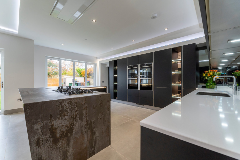 Inspiration for a large contemporary l-shaped kitchen pantry in Edinburgh with a built-in sink, flat-panel cabinets, black cabinets, composite countertops, grey splashback, mirror splashback, black appliances, ceramic flooring, an island, beige floors and multicoloured worktops.