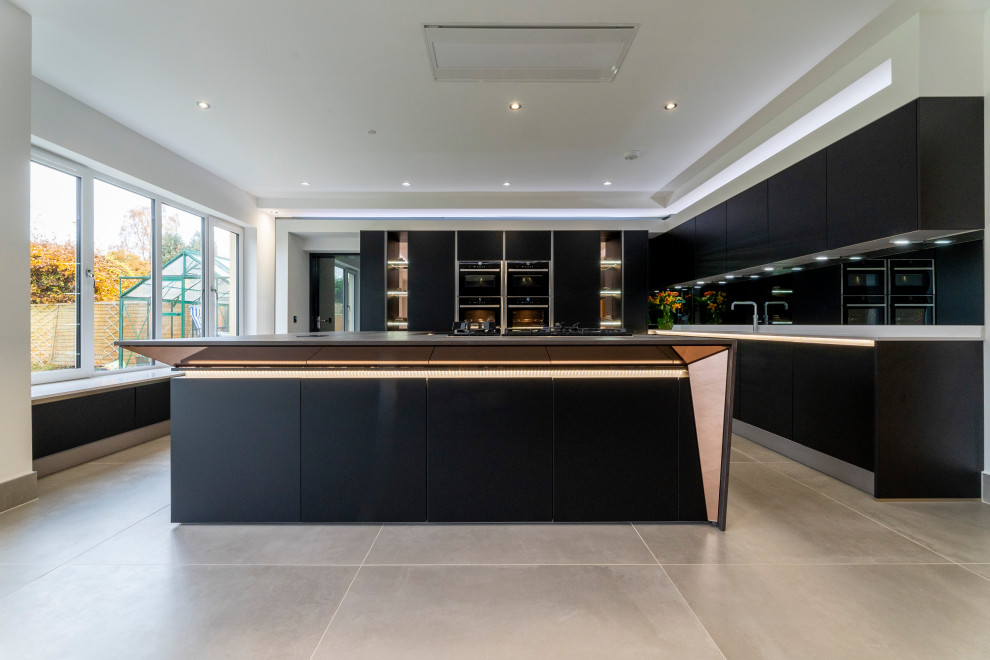 This is an example of a large contemporary l-shaped kitchen pantry in Edinburgh with a built-in sink, flat-panel cabinets, black cabinets, composite countertops, grey splashback, mirror splashback, black appliances, ceramic flooring, an island, beige floors and multicoloured worktops.