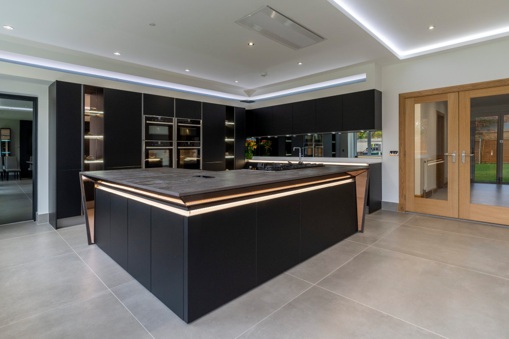 Photo of a large contemporary l-shaped kitchen pantry in Edinburgh with a built-in sink, flat-panel cabinets, black cabinets, composite countertops, grey splashback, mirror splashback, black appliances, ceramic flooring, an island, beige floors and multicoloured worktops.