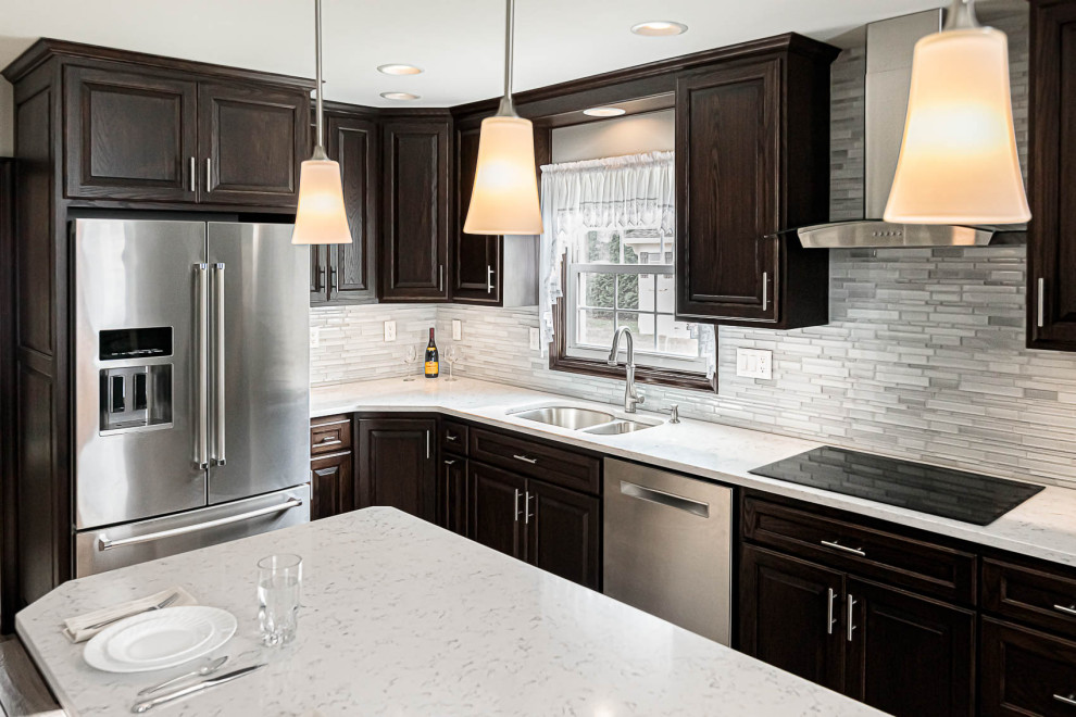 Small elegant single-wall porcelain tile and brown floor eat-in kitchen photo in Philadelphia with a double-bowl sink, raised-panel cabinets, dark wood cabinets, granite countertops, gray backsplash, glass tile backsplash, stainless steel appliances, an island and gray countertops