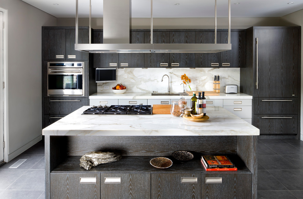 Modelo de cocina contemporánea con armarios con paneles lisos, salpicadero blanco, salpicadero de losas de piedra, electrodomésticos con paneles y puertas de armario de madera en tonos medios