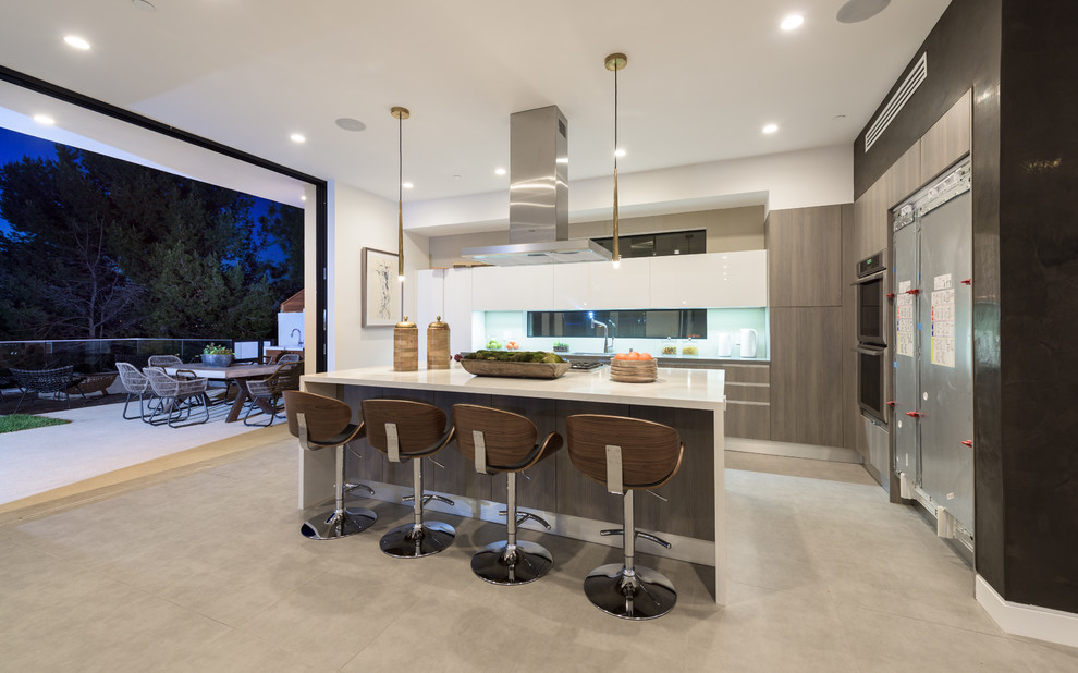 Large modern kitchen/diner in Los Angeles with stainless steel appliances, concrete flooring and an island.