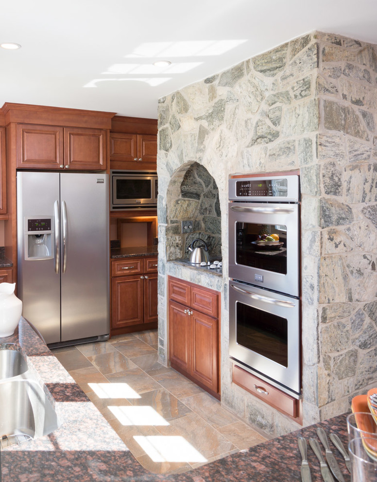Inredning av ett klassiskt stort kök, med en undermonterad diskho, luckor med upphöjd panel, skåp i mellenmörkt trä, granitbänkskiva, stänkskydd i sten, rostfria vitvaror och klinkergolv i porslin