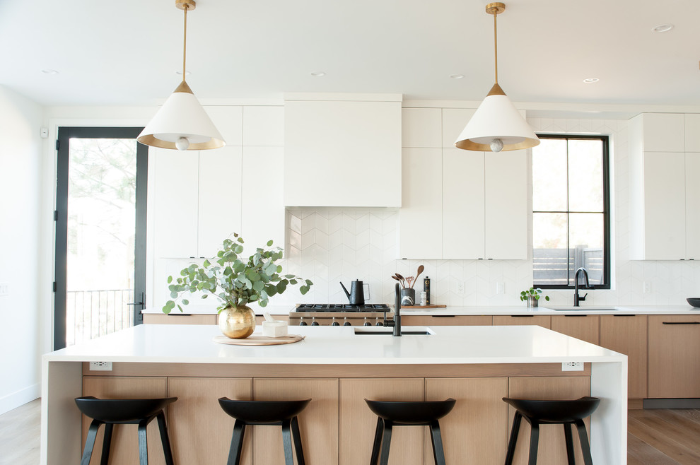 Esempio di una cucina scandinava con lavello sottopiano, ante lisce, ante in legno chiaro, paraspruzzi bianco, elettrodomestici da incasso, pavimento in legno massello medio, pavimento marrone e top bianco