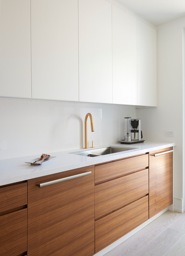 Medium sized modern single-wall kitchen/diner in Toronto with a submerged sink, flat-panel cabinets, light wood cabinets, composite countertops, white splashback, glass sheet splashback, integrated appliances, light hardwood flooring and no island.