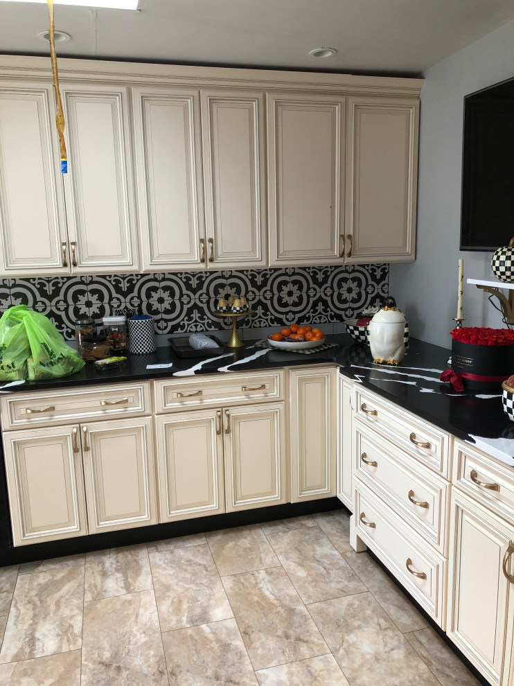 Inredning av ett eklektiskt mellanstort svart svart kök, med en rustik diskho, luckor med upphöjd panel, beige skåp, bänkskiva i kvarts, svart stänkskydd, stänkskydd i porslinskakel, svarta vitvaror, vinylgolv och flerfärgat golv