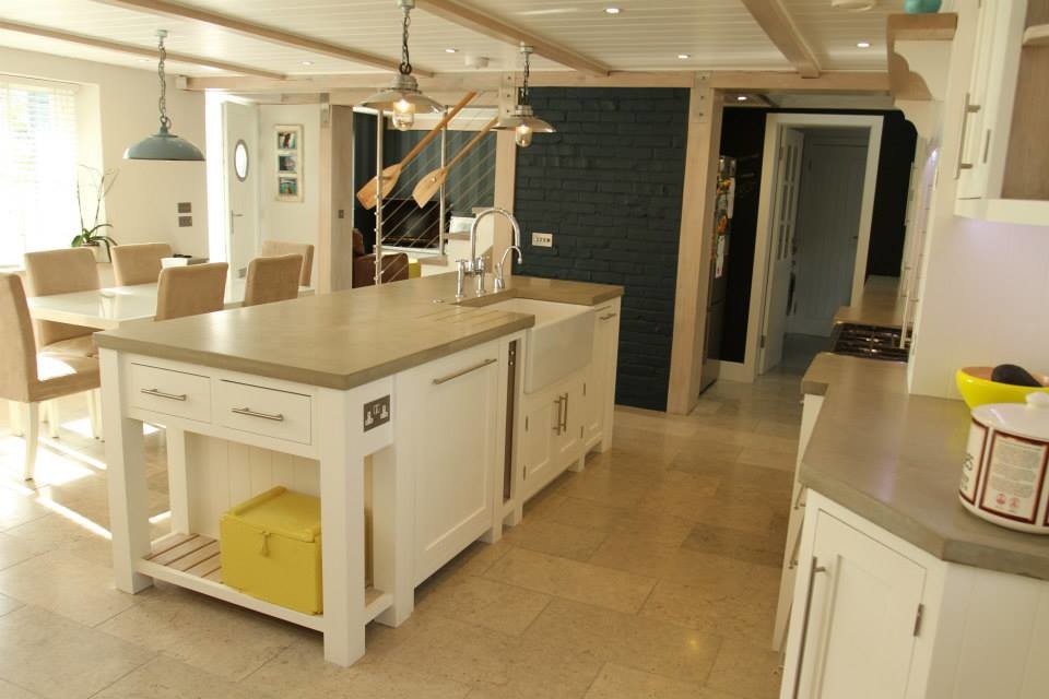 Maritim inredning av ett stort linjärt kök och matrum, med luckor med profilerade fronter, beige skåp, träbänkskiva och en köksö