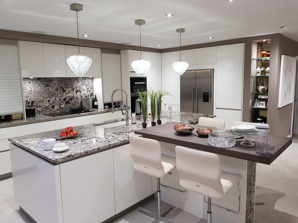 Foto på ett stort funkis grå kök, med en undermonterad diskho, släta luckor, vita skåp, granitbänkskiva, stänkskydd i sten, rostfria vitvaror, klinkergolv i porslin, en köksö, beiget golv och grått stänkskydd