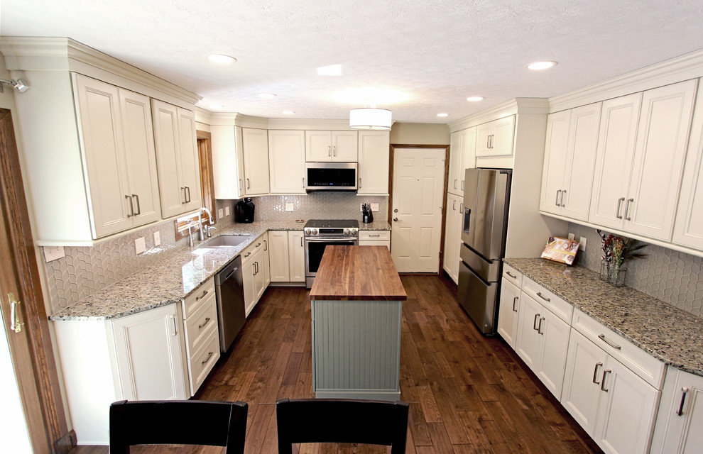 Inredning av ett modernt mellanstort grå grått kök, med en undermonterad diskho, luckor med infälld panel, vita skåp, granitbänkskiva, grått stänkskydd, stänkskydd i glaskakel, rostfria vitvaror, mellanmörkt trägolv, en köksö och brunt golv