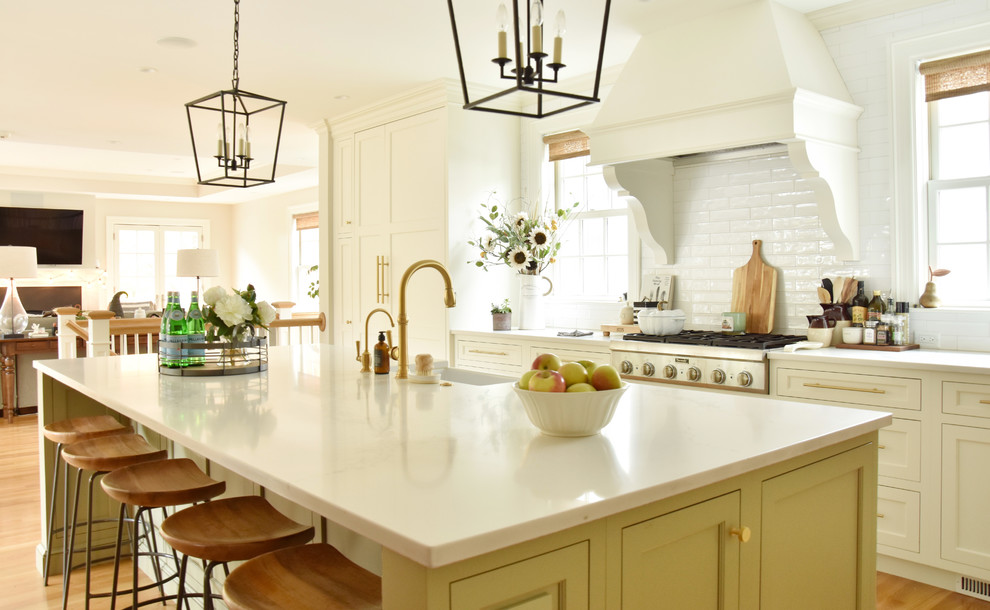 Inspiration for a timeless light wood floor kitchen remodel in Boston with a farmhouse sink, recessed-panel cabinets, quartz countertops, white backsplash, ceramic backsplash, an island and white countertops