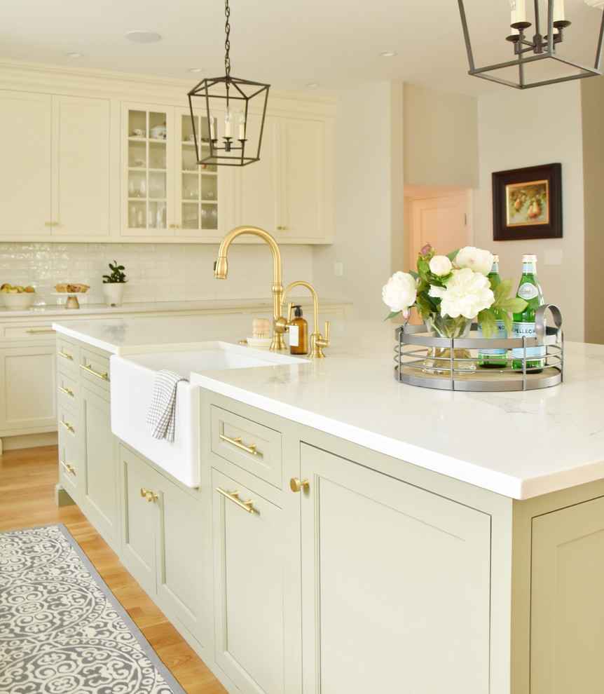 Klassische Küche mit Landhausspüle, Schrankfronten mit vertiefter Füllung, Quarzwerkstein-Arbeitsplatte, Küchenrückwand in Weiß, Rückwand aus Keramikfliesen, hellem Holzboden, Kücheninsel und weißer Arbeitsplatte in Boston