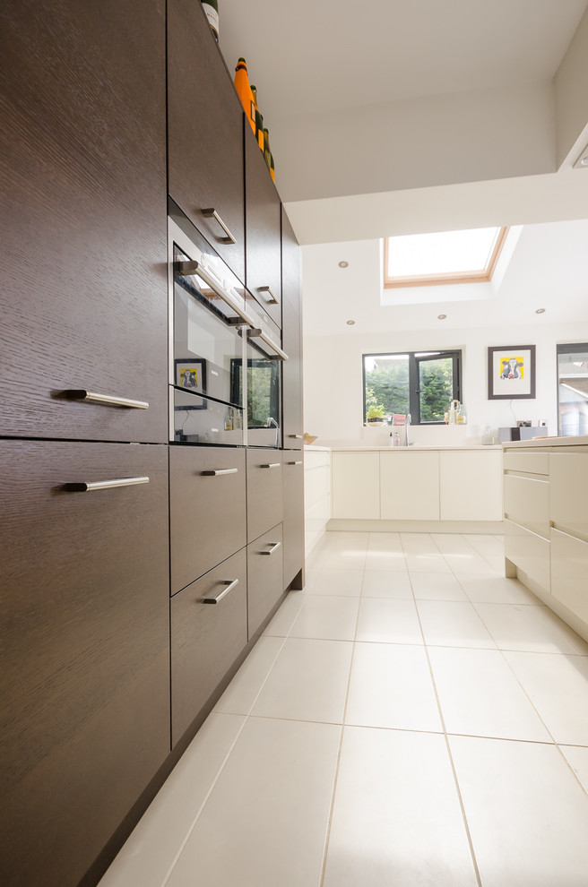 Photo of a medium sized contemporary kitchen/diner in Other with a submerged sink, flat-panel cabinets, white cabinets, composite countertops, white splashback, stainless steel appliances, laminate floors and a breakfast bar.