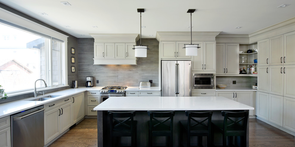 Inspiration for a large classic u-shaped kitchen/diner in Ottawa with beige cabinets, engineered stone countertops, grey splashback, ceramic splashback, stainless steel appliances, medium hardwood flooring, an island, a double-bowl sink and shaker cabinets.