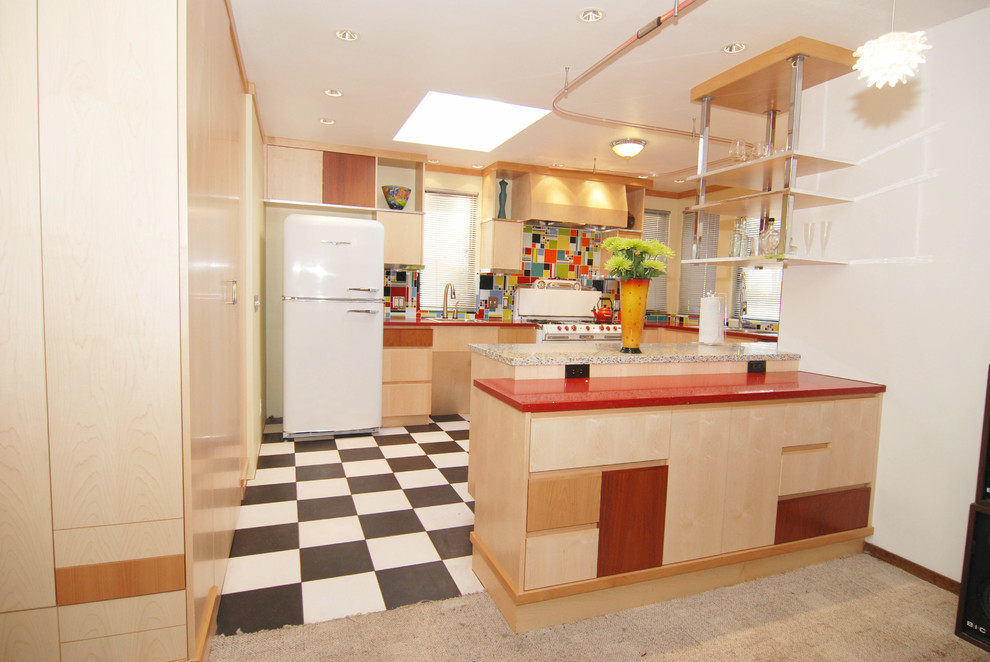 Modern inredning av ett mellanstort kök, med en dubbel diskho, släta luckor, skåp i ljust trä, bänkskiva i återvunnet glas, blått stänkskydd, stänkskydd i cementkakel, vita vitvaror, linoleumgolv och en halv köksö