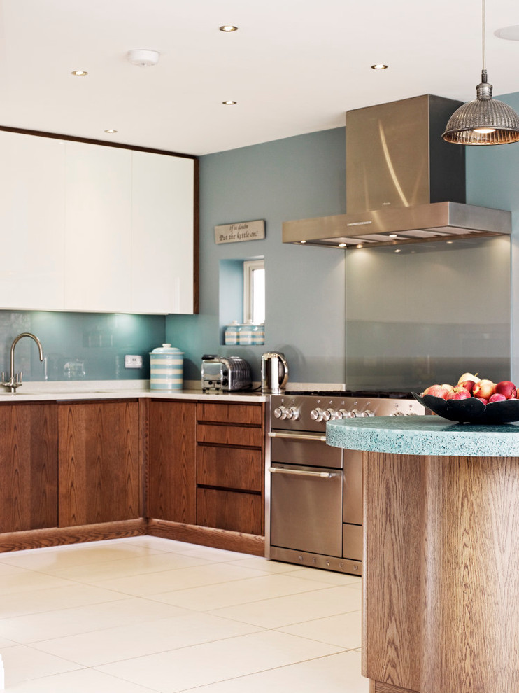 Photo of a medium sized contemporary kitchen/diner in London with flat-panel cabinets, medium wood cabinets, recycled glass countertops, stainless steel appliances and a breakfast bar.