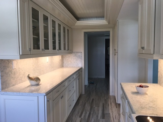 Inspiration for a medium sized coastal kitchen in Miami with recessed-panel cabinets, white cabinets, engineered stone countertops, stone slab splashback and white appliances.