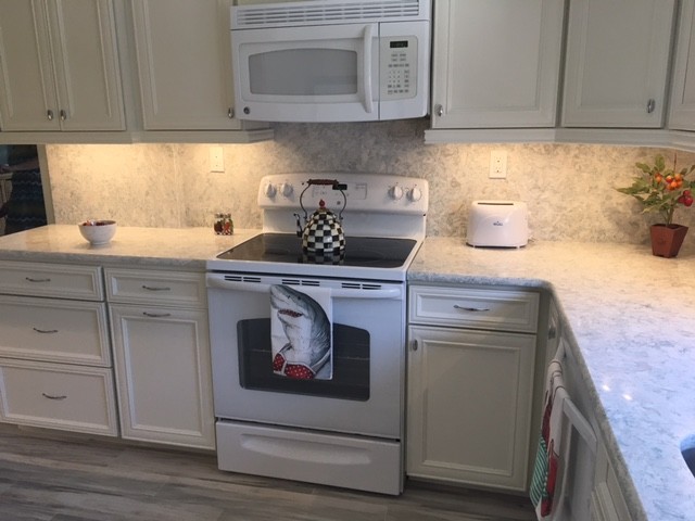 Example of a mid-sized beach style kitchen design in Miami with recessed-panel cabinets, white cabinets, quartz countertops, stone slab backsplash and white appliances