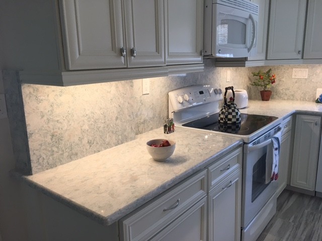 Mid-sized beach style kitchen photo in Miami with white cabinets, quartz countertops, stone slab backsplash, white appliances and recessed-panel cabinets