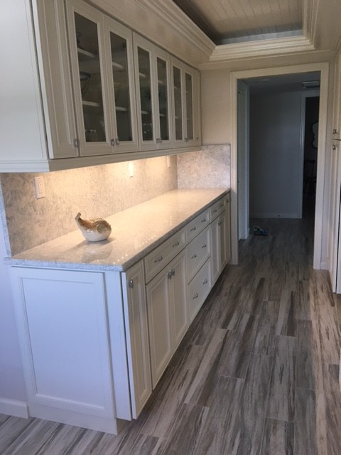 This is an example of a medium sized coastal kitchen in Miami with white cabinets, engineered stone countertops, stone slab splashback, white appliances and recessed-panel cabinets.