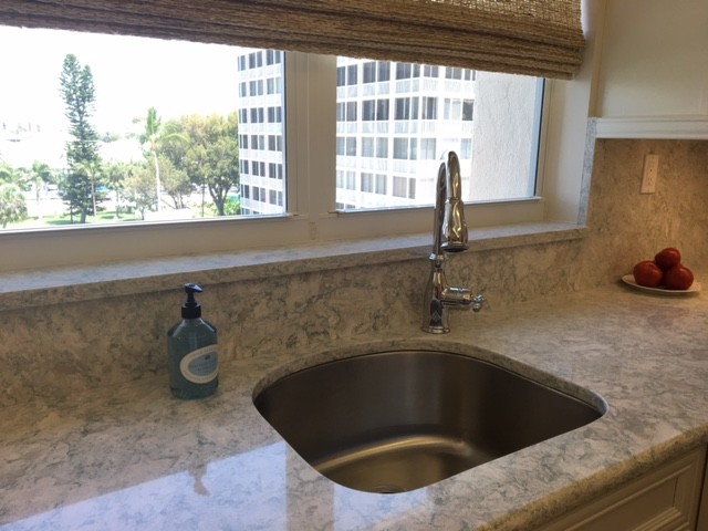 Mid-sized beach style kitchen photo in Miami with recessed-panel cabinets, white cabinets, quartz countertops, white appliances, an undermount sink and stone slab backsplash