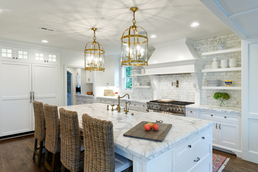 Classic l-shaped open plan kitchen in Cincinnati with a belfast sink, beaded cabinets, white cabinets, marble worktops, white splashback, marble splashback, stainless steel appliances, dark hardwood flooring, an island and brown floors.