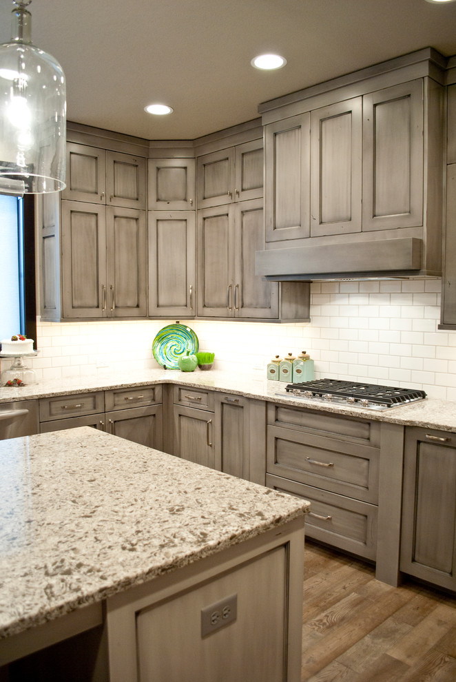 Photo of a large romantic u-shaped kitchen in Other with recessed-panel cabinets, distressed cabinets, engineered stone countertops, white splashback, stainless steel appliances and an island.
