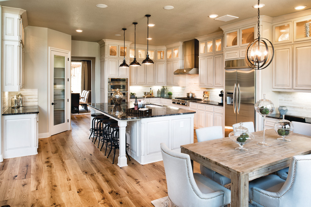 Elegant l-shaped medium tone wood floor eat-in kitchen photo in Philadelphia with an undermount sink, raised-panel cabinets, white cabinets, white backsplash, stainless steel appliances and an island